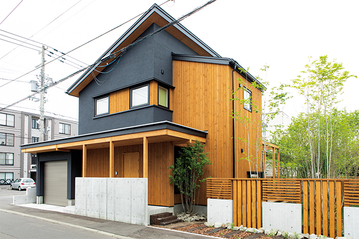 黒の塗り壁と板張りで構成された外観。木とコンクリートを組み合わせた塀は、適度に視線を遮る効果も